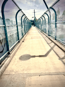 a shadow of a person is cast on a bridge with graffiti on the side