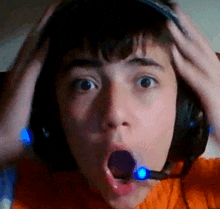 a young boy wearing headphones and a microphone is making a shocked face .