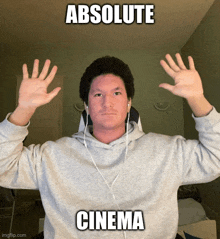 a man wearing headphones and a grey sweatshirt has his hands up in the air with the caption " absolute cinema "