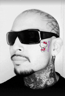a man with a hello kitty tattoo on his face has sunglasses on