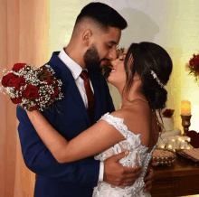 a bride and groom are kissing and the bride is wearing a bouquet of red roses