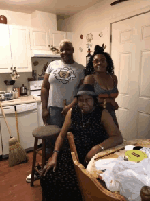 three women are posing for a picture in a kitchen with one wearing a t-shirt that says ' a '