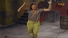 a man in overalls and suspenders is dancing in a room with a barrel in the background .