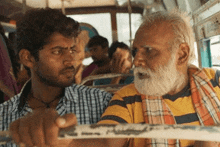 a man with a beard is talking to a younger man on a bus .