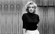 a black and white photo of marilyn monroe wearing a black turtleneck sweater and white skirt .