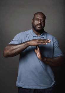 a man wearing a blue shirt is making a stop sign with his hands