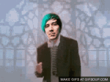 a man with green hair is dancing in front of a checkered wall with the words make gifs at gifsoup.com below him