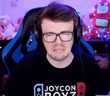 a man is wearing headphones and a joycon boyz shirt