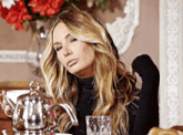 a woman is sitting at a table with a teapot and a cup of tea .