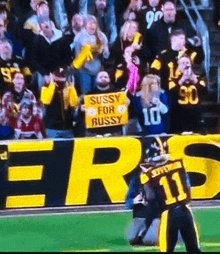 a football player holding a sign that says sussy for russy on it