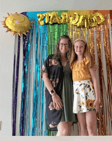 a woman and a girl are posing for a picture in front of a backdrop that says " rainbow "