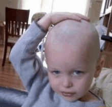 a young boy with a bald head is sitting on a couch .