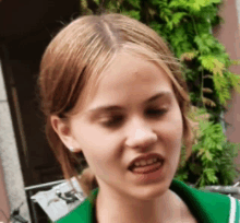 a young girl wearing a green jacket is smiling and looking at the camera