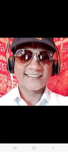 a man wearing sunglasses and headphones is smiling for the camera .