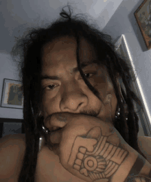 a man with dreadlocks has a tattoo on his wrist that says ' i love you '