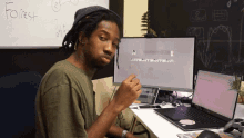 a man sits at a desk in front of a white board that has the word forest written on it