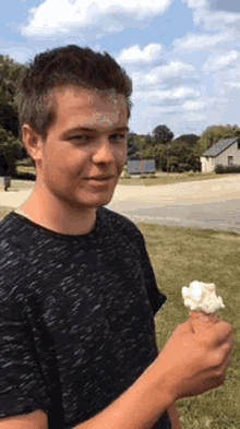 a young man is holding a cone of ice cream in his hand and has ice cream on his face .