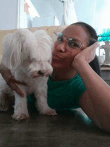 a woman with glasses holds a small white dog in her arms