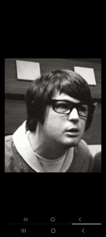 a black and white photo of a man wearing glasses and a white shirt