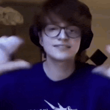 a young man wearing glasses and headphones is holding a controller .