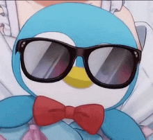 a blue penguin wearing sunglasses and a red bow tie .