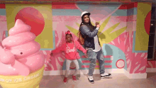 a man and a little girl are posing for a picture in front of a large ice cream cone .