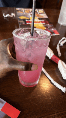 a person holding a pink drink with a straw in it