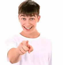a young man in a white shirt points at the camera
