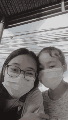 two young girls wearing face masks and glasses pose for a picture