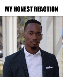 a man in a suit and white shirt is standing in front of a sign that says my honest reaction