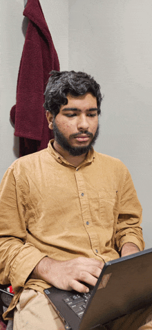 a man in a brown shirt is using a laptop