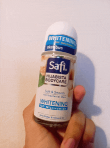 a person is holding a bottle of safi hijabista bodycare