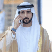 a man with a beard is talking on a cell phone while wearing a turban .