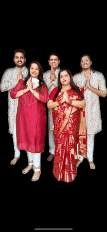 a group of people posing for a picture with their hands folded in prayer