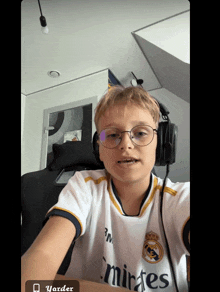 a young boy wearing glasses and a white shirt that says emirates