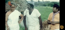 a group of men are standing in a field and one of them is wearing a white shirt with the letter t on it