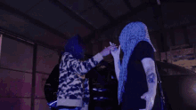 a person with a purple scarf around their head is shaking hands with another person .
