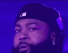 a close up of a man with a beard wearing a hat and earring .