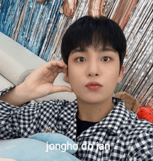 a young man wearing a plaid shirt with the name jongho do ian written on the bottom