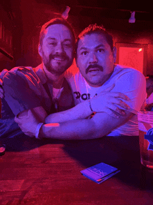 two men posing for a picture with one wearing a shirt that says ' por ' on it