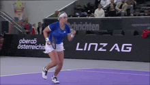 a tennis player is running on a court in front of a linzag sign