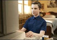 a boy in a blue shirt is typing on a computer keyboard