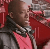 a man wearing a black jacket and a red shirt is sitting in the stands