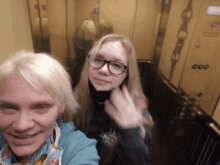 a woman and a girl are taking a selfie in an elevator with the number 000 on the wall