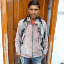 a man standing in front of a door with a scarf around his neck