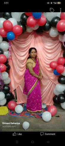 a woman in a pink saree stands in front of a wall of balloons