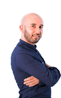 a bald man with a beard wearing a blue shirt is standing with his arms crossed