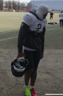 a football player with the number 2 on his jersey is holding a helmet