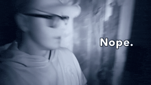 a blurry picture of a person with glasses and the word nope behind them