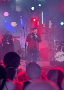 a man sings into a microphone in front of a drum set that says ' twig ' on it